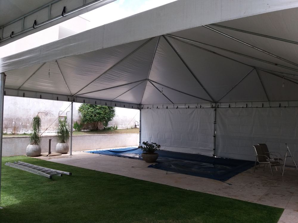 Tenda piramidal com fechamento lateral branco protegendo área de piscina